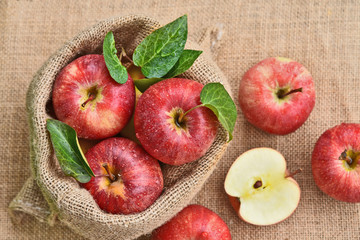 Fresh many Gala apple with green leaf with water drop in sack bag and sack background.
