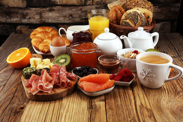 breakfast on table with bread buns, croissants, coffe and juice.