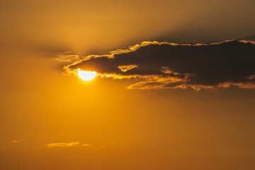 Vivid orange sunset with small cloud.