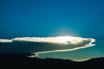 sun behind clouds on sunset