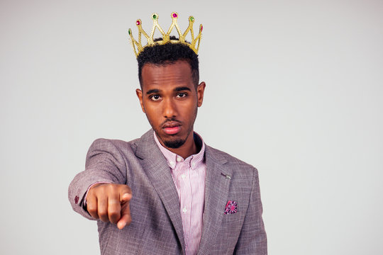smart african american successful and rich businessman in a stylish suit and the golden crown on his head on white background in studio shot. the concept of well-deserved respect and luck