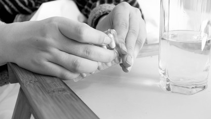Black and white image of female hands unpacking pills
