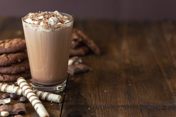 Cup of cocoa with marshmallows and chocolate cookies on dark wooden background
