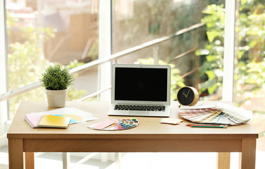 Fototapeta premium Designer's workplace with laptop and paint color palette samples on table