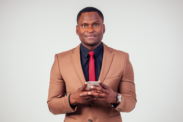 African businessman using phone in brown suit, black shirt and red tie on white background in studio shot © yurakrasil