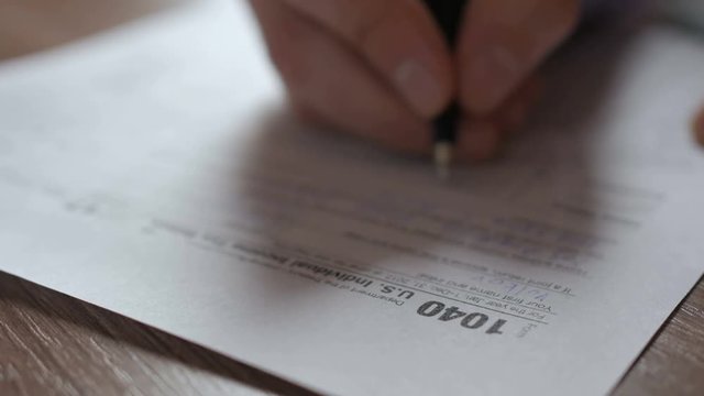 Man filling US tax form. tax form us business income office hand fill concept. Closeup.  Man Is Checking The Box Of Filing Status In The US Individual Income.  Tax Return Form 1040