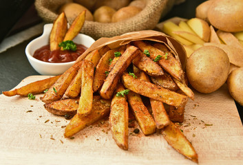 Homemade Crispy Seasoned French Fries..French fries  with spicy seasoning in brown paper bag on...