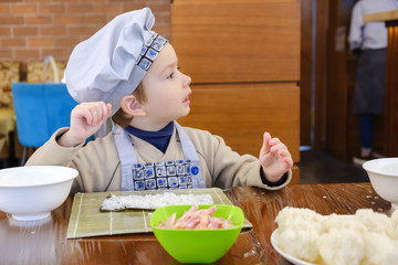 Cooking of traditional sushi rolls. The boy is dressed as a cook.