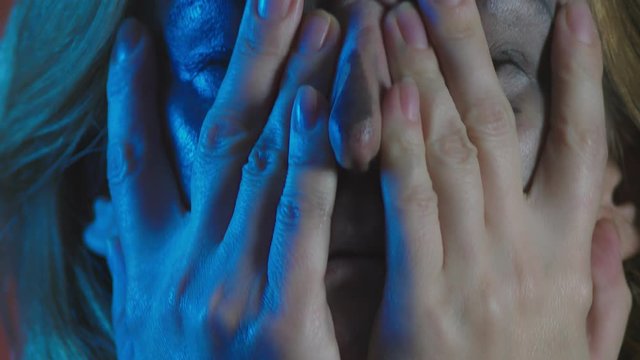 4k, slow motion, Halloween. tired woman in the costume of a terrible witch, erases the make-up from her face with her hands. close-up