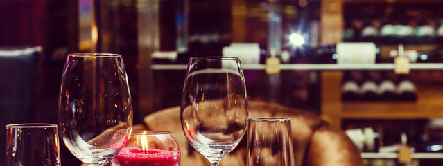 Two glasses of wine white and red standing on a table with candle in the sun light