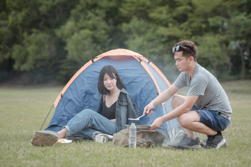 man and woman sitting in chairs outside the tent. Couple camping in nature