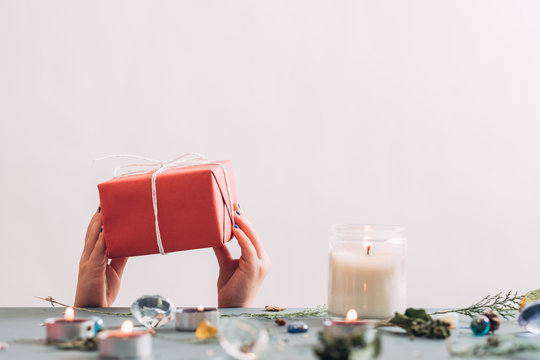 christmas presents and holiday celebration. hands holding a red dift box behind the table. festive seasonal decor on the surface. copy space concept