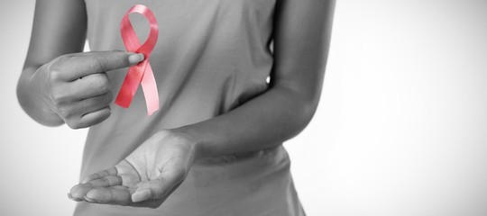 Woman holding ribbon between fingers for breast cancer awareness
