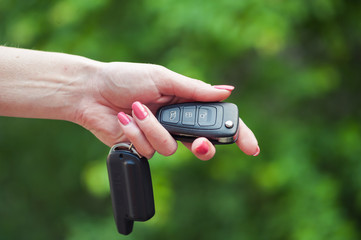 Key from the car in a female hand. Car seller. Opening and signaling
