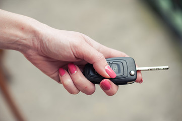 Key from the car in a female hand. Car seller. Opening and signaling
