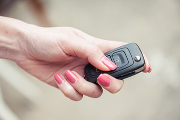Fototapeta premium Key from the car in a female hand. Car seller. Opening and signaling