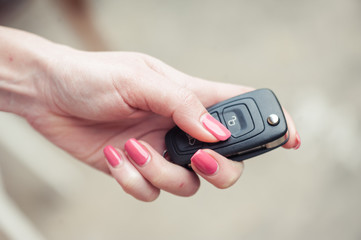 Key from the car in a female hand. Car seller. Opening and signaling
