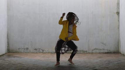 dancing woman young mixed race street dancer performing freestyle hip hop moves enjoying modern dance expression practicing in grungy warehouse wearing yellow jacket