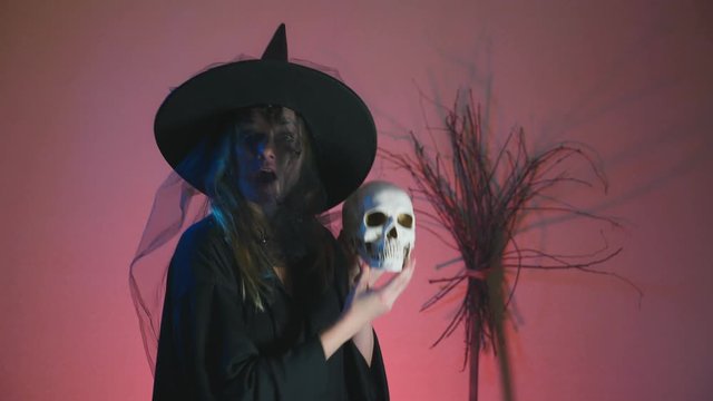4k, slow-motion, halloween. A woman in the costume of a terrible witch dances with a skull in her hands. copy space