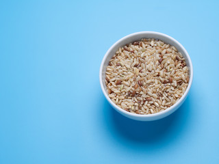 brown rice in white cup on a blue background