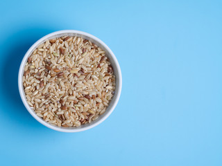 brown rice in white cup on a blue background