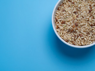 brown rice in white cup on a blue background