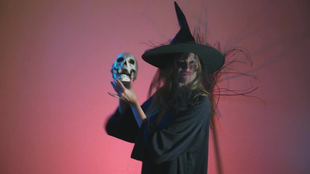 4k, slow-motion, halloween. A woman in the costume of a terrible witch dances with a skull in her hands. copy space
