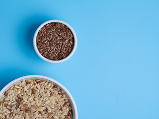 brown rice and flax in white cups on a blue background