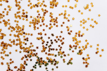 Festive golden stars of confetti on a white background.