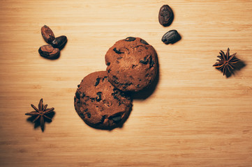 Top view of round crispy chocolate biscuits with cocoa chips, on textured wooden background