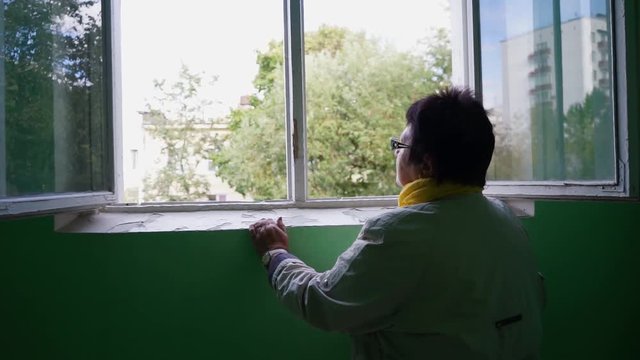 an elderly woman looking out the window MLS 2