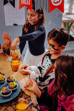 Cupcakes for Halloween. Three beautiful cute children eating cupcakes while having Halloween party in kindergarten