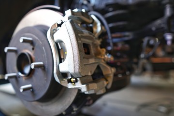 Selective focus of Brake Disc of the vehicle for repair.Automobile mechanic in process of new tire replacement.Car brake repairing in garage.Car Service and technician concept.