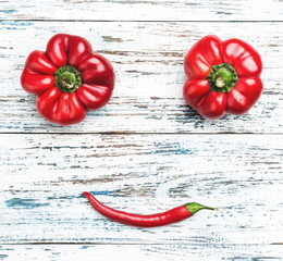 Composition of different types of red peppers, vegetable smile. Top view on old white-blue background