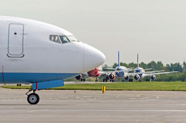 Delays and queues traffic aircraft before departure. In the foreground the nose of a landed plane.