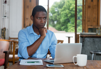 Thinking african american man with laptop