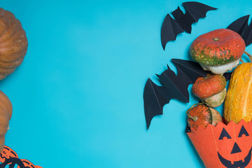 Halloween, decoration and scary concept - black paper bats, pumpkins over blue background. Free place for text.