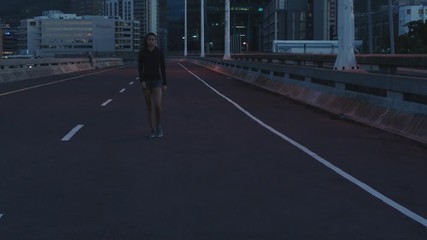 young woman runner athlete walking resting exhausted after running exercise workout in urban city at night