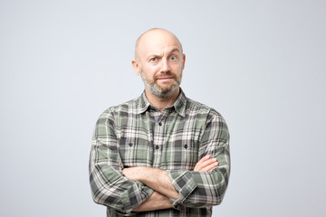 grumpy mature european man posing in studio with arms folded, feeling insulted while having quarrel with his girlfriend