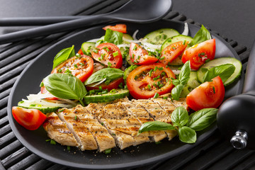 Vegetable salad and grilled chicken on a black background. Healthy food. Diet.