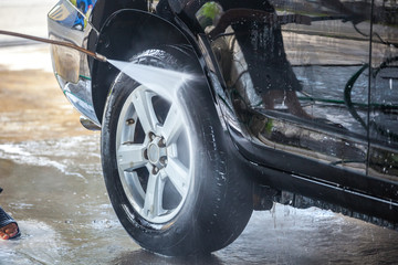 Car washing. Cleaning car with high pressure water and foam