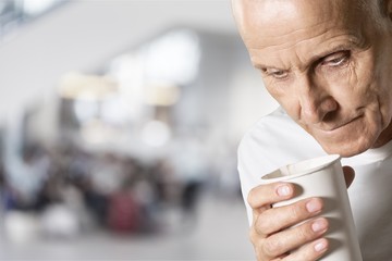 Thoughtful senior man holding white cup