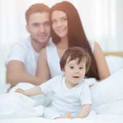 Obraz premium Portrait of a joyful family sitting on the bed at home