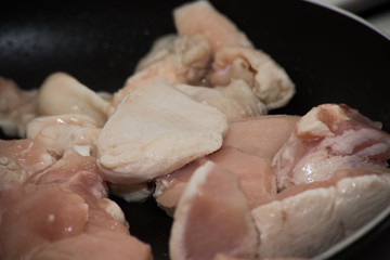 Chopped chicken pieces are fried in a frying pan