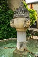 Old stone fountain with women heads in french medieval city of Vaison-la-Romaine.