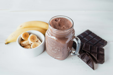 Banana and chocolate smoothie in the glass jar milkshakes, natural and organic drink