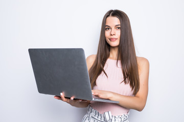 Portrait of happy woman standing with laptop isolated on gray background