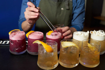 Professional Bartender is making fresh cocktail at bar counter, close-up