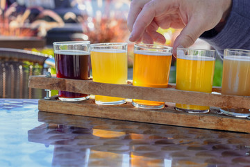 Man sampling beer at an outdoor beer garden, hand in frame