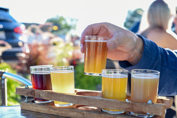 Man sampling beer at an outdoor beer garden, hands only